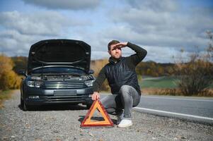 hombre con roto coche en el medio de el la carretera. foto