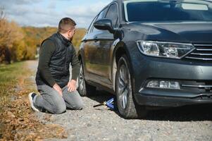 A young man with a black car that broke down on the road,copy space. photo