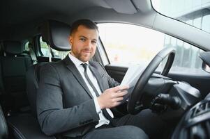 hombre de estilo y estatus. un joven apuesto con traje completo sonriendo mientras conduce un auto foto