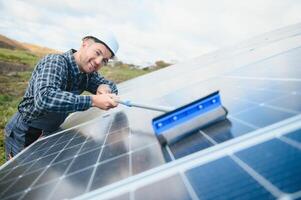 technician operating and cleaning solar panels at generating power of solar power plant photo