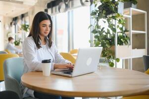 Beautiful Caucasian woman dreaming about something while sitting with portable net-book in modern cafe bar, young charming female freelancer thinking about new ideas during work on laptop computer photo