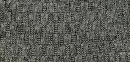 Background with gray knitted leaf shape, knitting pattern with cables. Top view, close-up. Handmade knitting wool photo