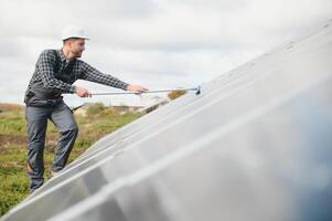 technician operating and cleaning solar panels at generating power of solar power plant photo