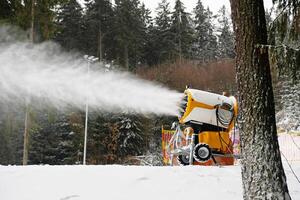 Snow cannon makes artificial snow. Snowmaking systems sprays water to produce snow. photo