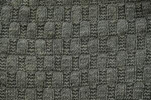 Background with gray knitted leaf shape, knitting pattern with cables. Top view, close-up. Handmade knitting wool photo