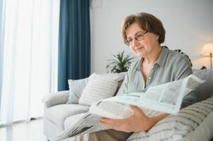 más viejo mujer relajarse y leyendo periódico foto