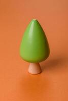 Wooden model of a tree with a green crown and trunk on a orange background photo