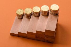 Conceptual composition of wooden steps with coins, model of a house photo