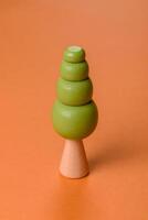 Wooden model of a tree with a green crown and trunk on a orange background photo