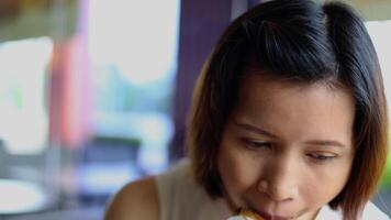 een vrouw aan het eten een Hamburger. vervagen achtergrond. video