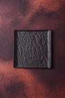 Empty black square ceramic plate on dark concrete background photo
