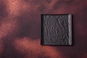 Empty black square ceramic plate on dark concrete background photo