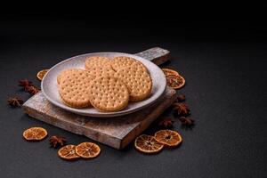 Round dotted snack snack cookies with cream on a dark concrete background photo