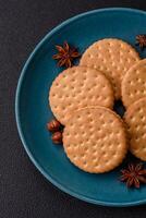 Round dotted snack snack cookies with cream on a dark concrete background photo