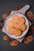 Round dotted snack snack cookies with cream on a dark concrete background photo