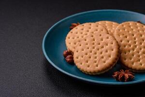 Round dotted snack snack cookies with cream on a dark concrete background photo