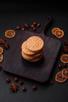 Round dotted snack snack cookies with cream on a dark concrete background photo