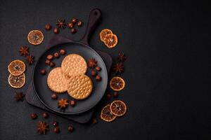 Round dotted snack snack cookies with cream on a dark concrete background photo