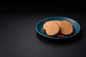 Round dotted snack snack cookies with cream on a dark concrete background photo