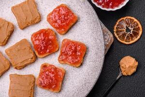 Delicious nutritious sandwiches with peanut butter, strawberry jam photo