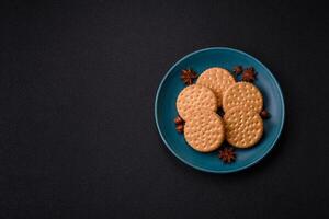 Round dotted snack snack cookies with cream on a dark concrete background photo