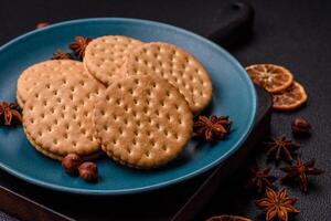 Round dotted snack snack cookies with cream on a dark concrete background photo