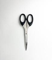 Stainless steel closed scissors with black colored handle. Cutting object photography isolated on plain studio background. photo