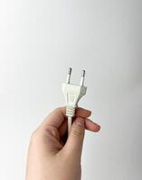 Hand holding white colored electronic object plug cable isolated photography on white studio background. photo