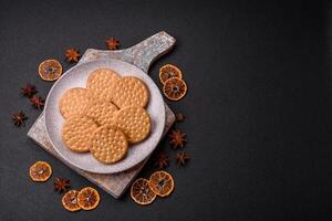 Round dotted snack snack cookies with cream on a dark concrete background photo