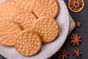 Round dotted snack snack cookies with cream on a dark concrete background photo