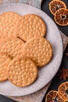 Round dotted snack snack cookies with cream on a dark concrete background photo