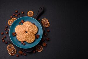 Round dotted snack snack cookies with cream on a dark concrete background photo