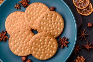 Round dotted snack snack cookies with cream on a dark concrete background photo