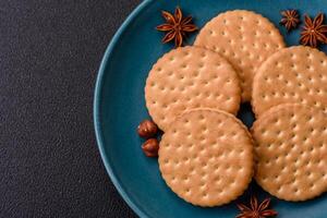 Round dotted snack snack cookies with cream on a dark concrete background photo