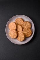 Round dotted snack snack cookies with cream on a dark concrete background photo