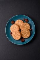 Round dotted snack snack cookies with cream on a dark concrete background photo