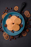 Round dotted snack snack cookies with cream on a dark concrete background photo