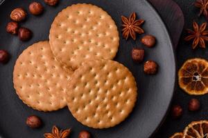 Round dotted snack snack cookies with cream on a dark concrete background photo