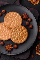 Round dotted snack snack cookies with cream on a dark concrete background photo