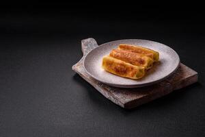 Delicious fried pancakes with filling rolled on a dark concrete background photo