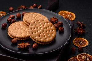 Round dotted snack snack cookies with cream on a dark concrete background photo