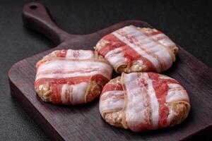 Round minced chicken or pork cutlet wrapped in bacon with salt, spices and herbs photo