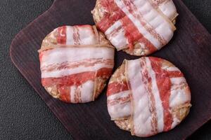 Round minced chicken or pork cutlet wrapped in bacon with salt, spices and herbs photo