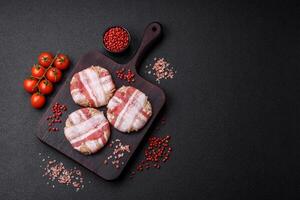 Round minced chicken or pork cutlet wrapped in bacon with salt, spices and herbs photo