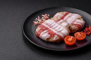 Round minced chicken or pork cutlet wrapped in bacon with salt, spices and herbs photo