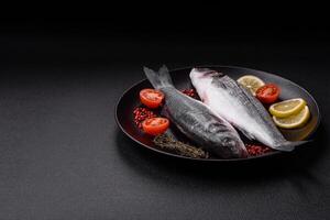 Fresh raw ocean sea bass fish with salt, spices and herbs photo