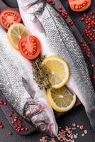 Fresh raw ocean sea bass fish with salt, spices and herbs photo