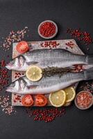 Fresh raw ocean sea bass fish with salt, spices and herbs photo