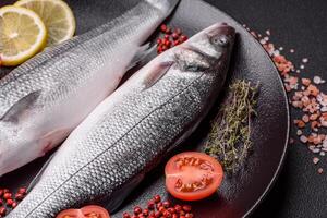 Fresh raw ocean sea bass fish with salt, spices and herbs photo