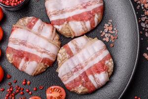 Round minced chicken or pork cutlet wrapped in bacon with salt, spices and herbs photo